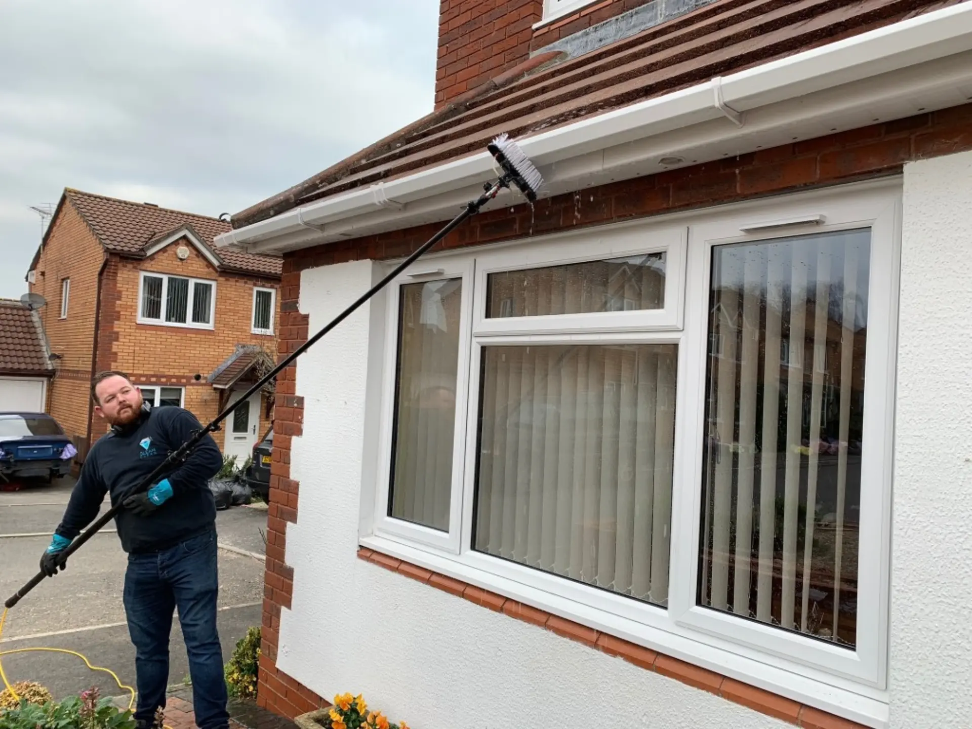 Professional exterior cleaner using a water-fed pole on a residential property in Hertfordshire